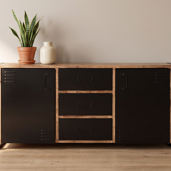 Dressoir met zwarte metalen deuren en houten lades in een lichte woonkamer, met een plant en vaas erop
