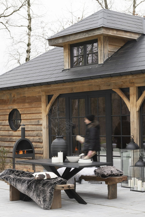 Bruin houten bankje van 190x38x46 cm met een robuuste uitstraling, gestyled met zachte vachten op een terras.