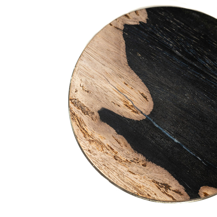 Rond tafelblad van zwart versteend hout met zichtbare natuurlijke houtnerf en textuur.
