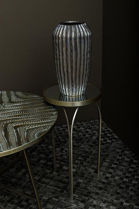 Ronde gouden bijzettafel Rikka van PTMD met een ijzeren frame en spiegelend blad in een stijlvol interieur.