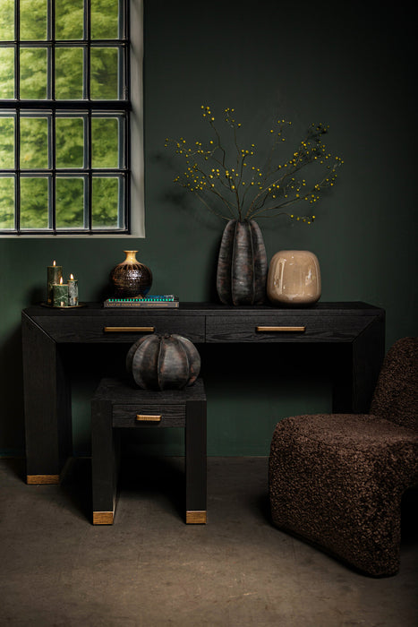 Zwarte PTMD bijzettafel van houtfineer met zichtbare houtnerf en goudkleurige accenten in een sfeervol interieur.