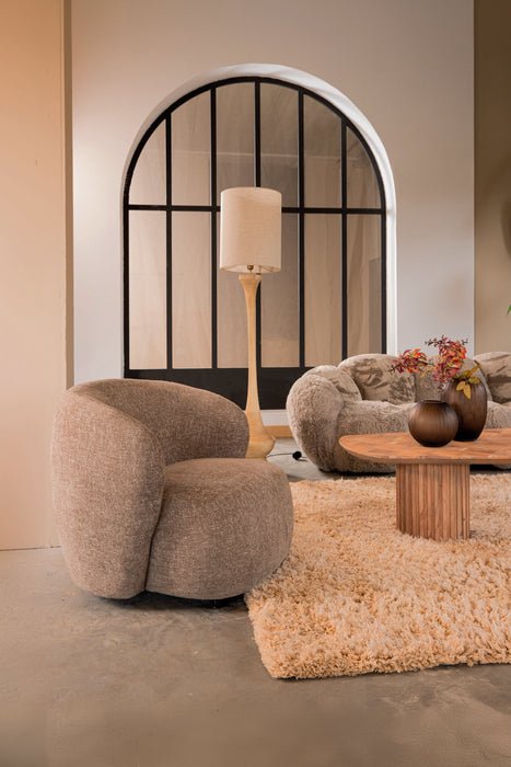 Moderne taupekleurige fauteuil van PTMD in polyester met een ronde, organische vorm in een sfeervol interieur.
