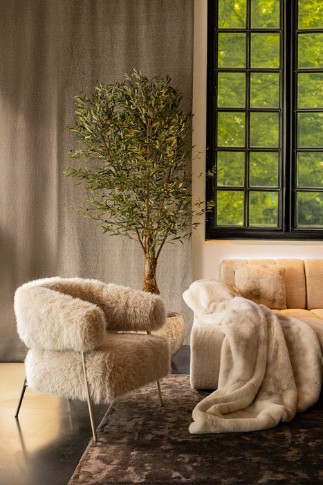 Luxe beige fauteuil van PTMD met zachte polyester bekleding en slank onderstel in een sfeervol interieur.
