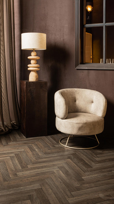 Beige polyester fauteuil Carice van PTMD met een slank metalen onderstel in een sfeervol interieur.