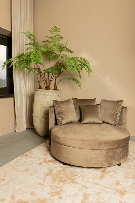 Ronde zandkleurige fauteuil van PTMD in zachte fluwelen stof met bijpassende sierkussens in een modern interieur.
