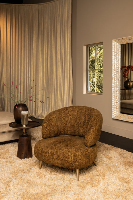 Moderne amberkleurige fauteuil van polyester met een slank metalen onderstel in een sfeervol interieur.