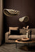 Twee beige en zwarte rotan hanglampen met golvend design boven een bruine bank in een modern interieur.