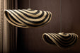 Twee beige en zwarte rotan hanglampen van PTMD met golvend design en 36 cm diameter.