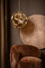 PTMD Tijdloze hanglamp in goudkleurig glas met geometrisch design, 49x49x50 cm, hangend boven een bruine fauteuil.