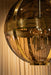 Ronde PTMD hanglamp van goudkleurig messing en glas, 66x66x91 cm, met een luxe bolvormig design en zichtbare lichtbronnen.