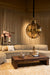 Grote ronde PTMD hanglamp van glas met messingkleurige details in een sfeervol interieur.