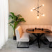 LABEL51 Modula 2-zits eetkamerbank in naturel bouclé met zwart metalen frame aan een houten eettafel.