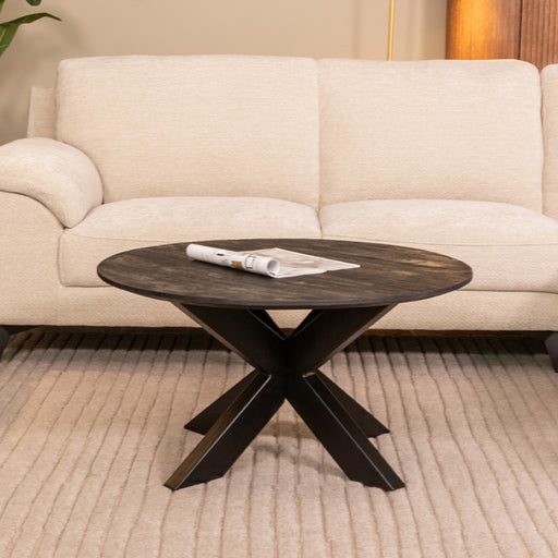 LABEL51 Otis ronde salontafel van 80 cm met zwart mangohouten blad en kruispoot in een modern interieur.