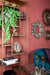 Gouden ijzeren vakkenkast van 30x60x195 cm met decoratieve woonaccessoires tegen een roze muur.
