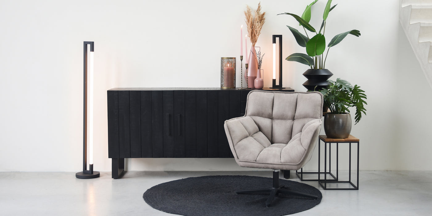 Zwarte dressoir met grijze fauteuil op zwart vloerkleed